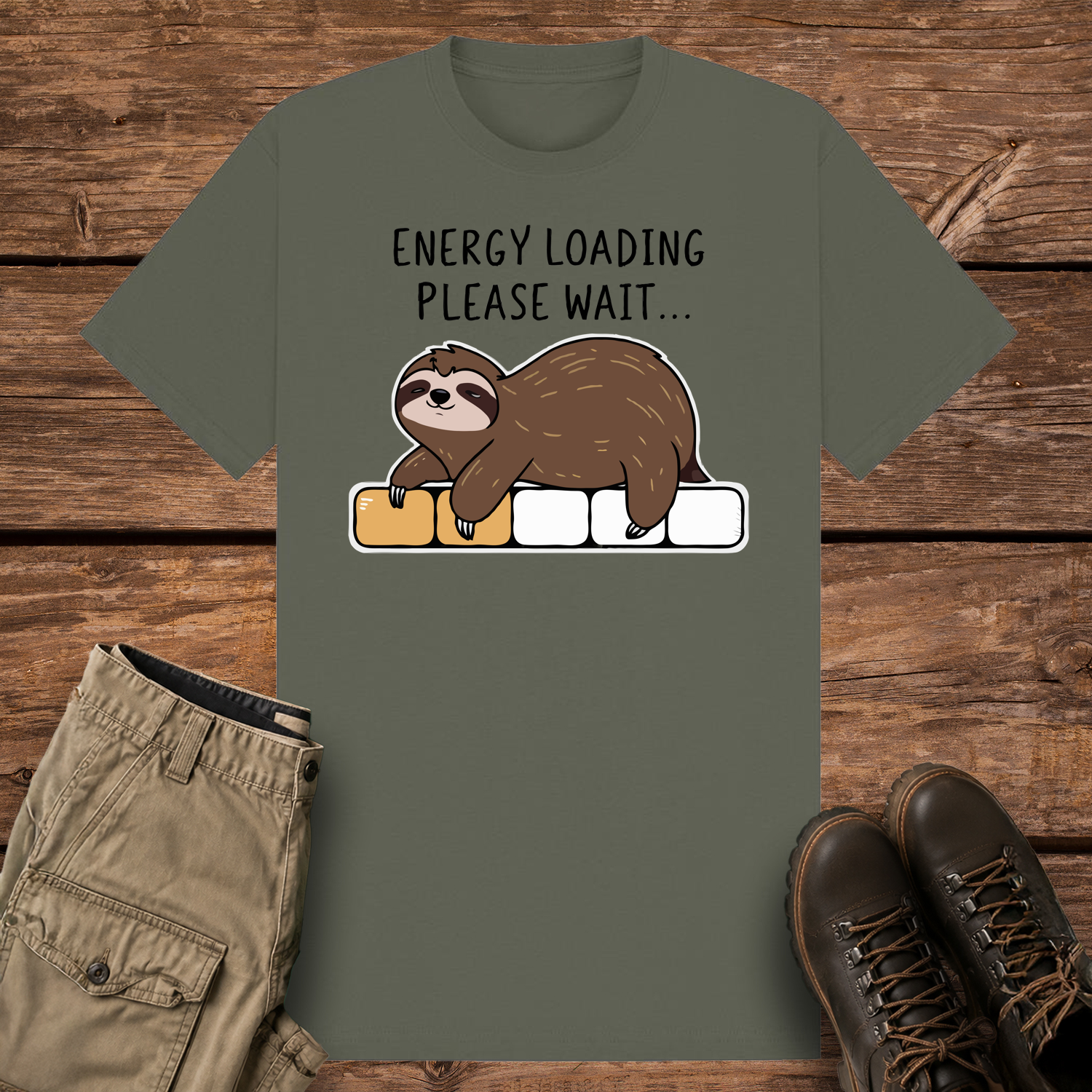 A khaki olive-colored graphic t-shirt featuring a cute cartoon illustration of a brown sloth lying face down on a progress loading bar that is only partially filled with yellow. Above the design, black text reads "ENERGY LOADING PLEASE WAIT..."