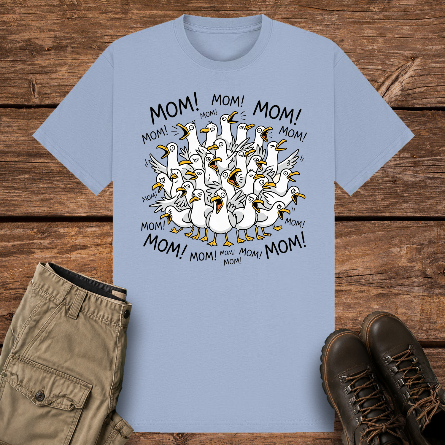 A pastel blue-colored graphic t-shirt featuring a funny cartoon illustration of a crowded flock of squawking seagulls with their beaks wide open. The word "MOM!" is written repeatedly in a circle surrounding the frantic birds.