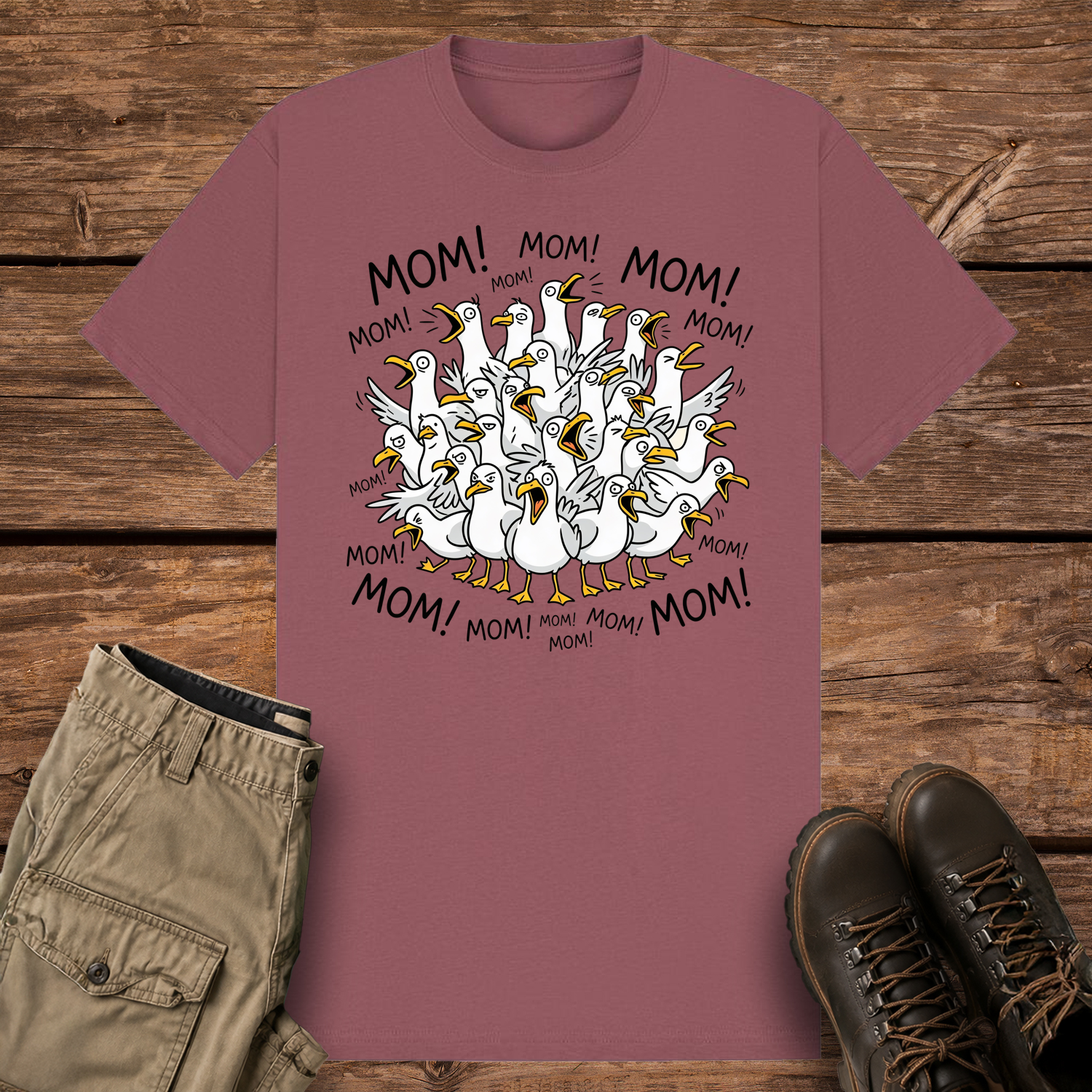 A mauve-colored graphic t-shirt featuring a funny cartoon illustration of a crowded flock of squawking seagulls with their beaks wide open. The word "MOM!" is written repeatedly in a circle surrounding the frantic birds.